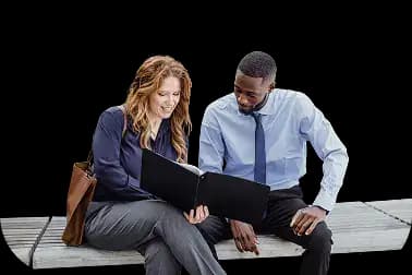 Two business professionals sitting on a bench, one holding an open folder and pointing at a document while the other looks on and smiles, illustrating collaborative review and agreement for trademark registration and brand protection.