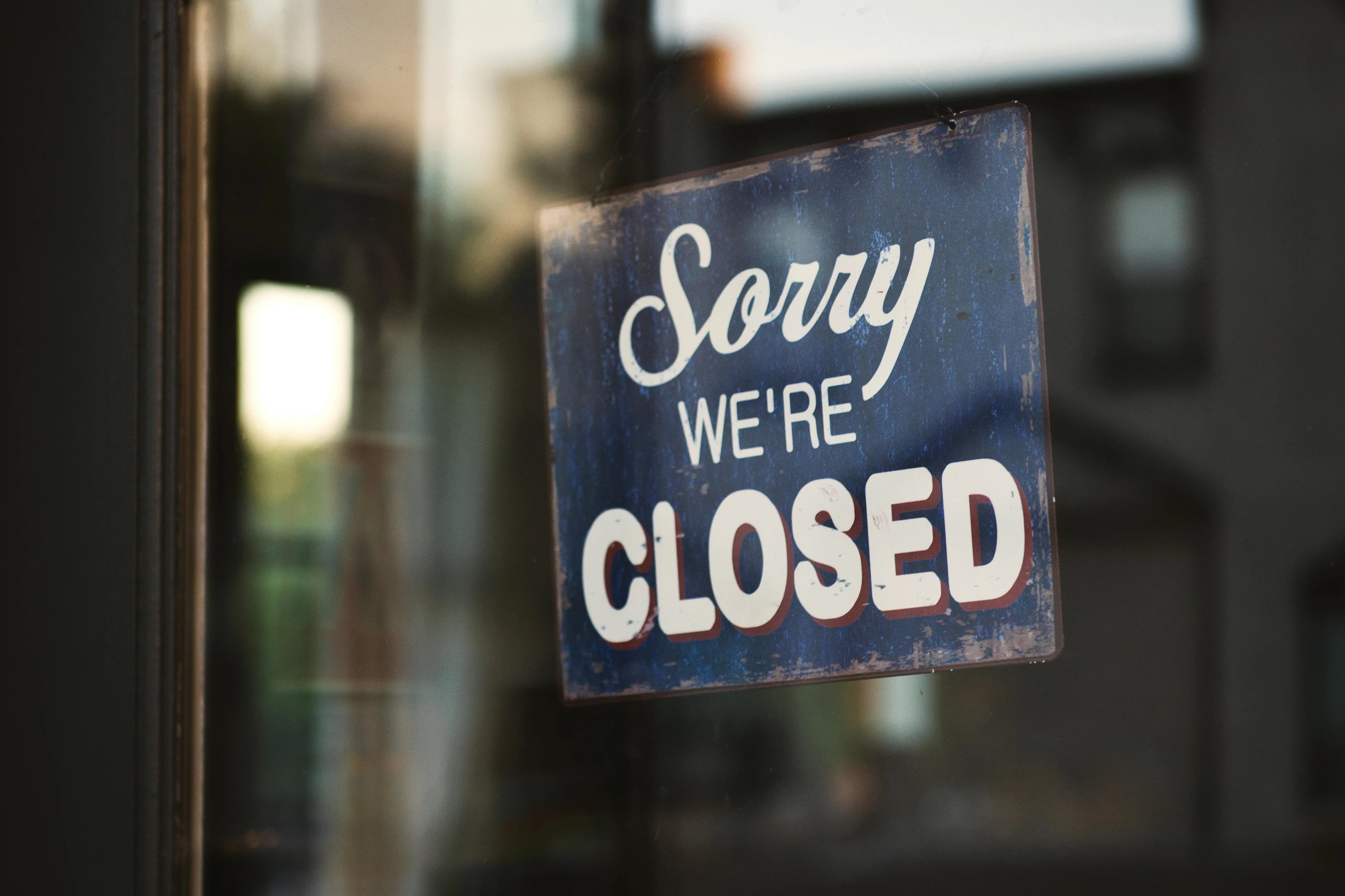 Sorry We're Closed' sign on a storefront window, symbolizing the permanent closure and dissolution of a business entity.
