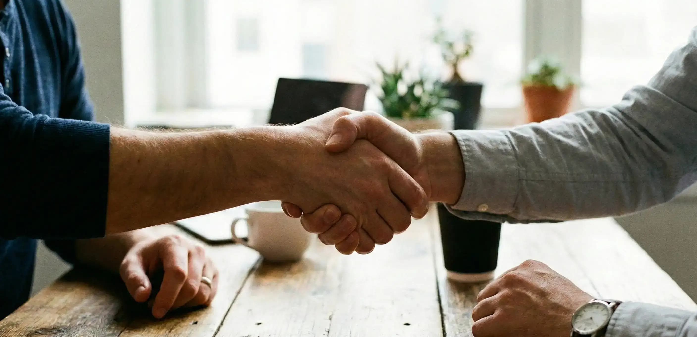 Business partners shaking hands over a table to finalize a Florida partnership registration.