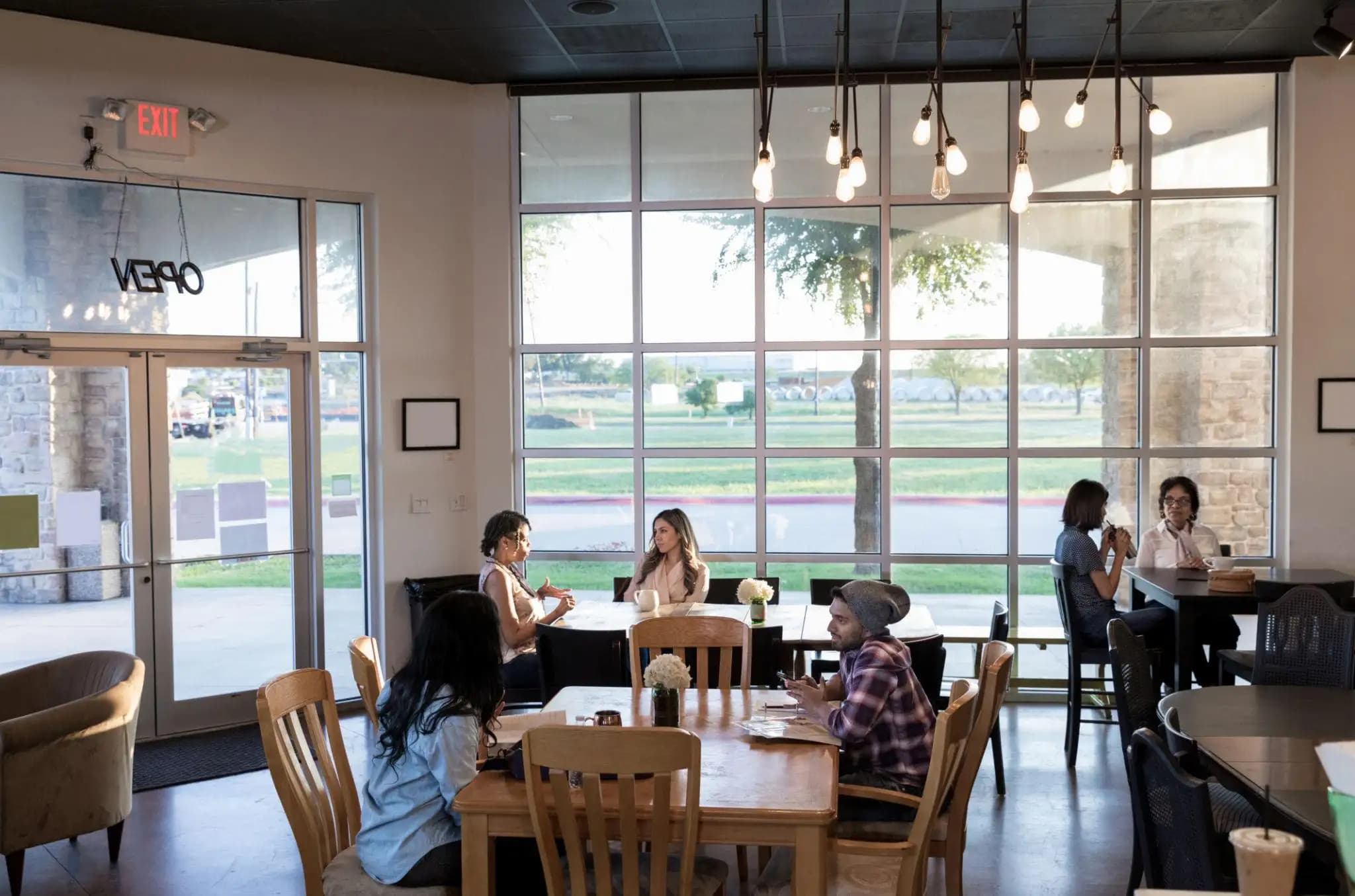 Two people reviewing paperwork at a table in a bright cafe, discussing a DBA vs LLC.