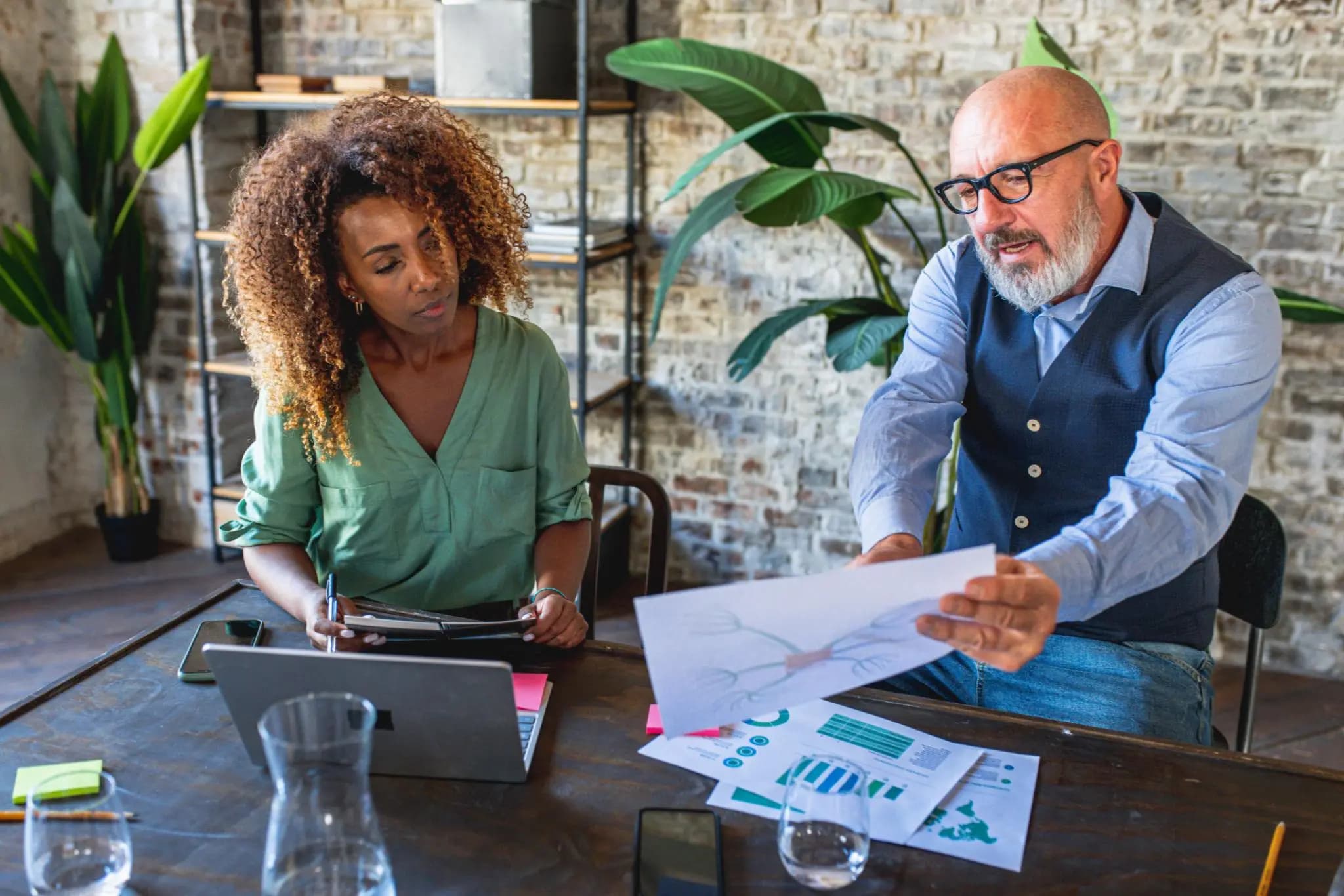 Two professionals reviewing financial charts and a diagram to map out franchise tax requirements.