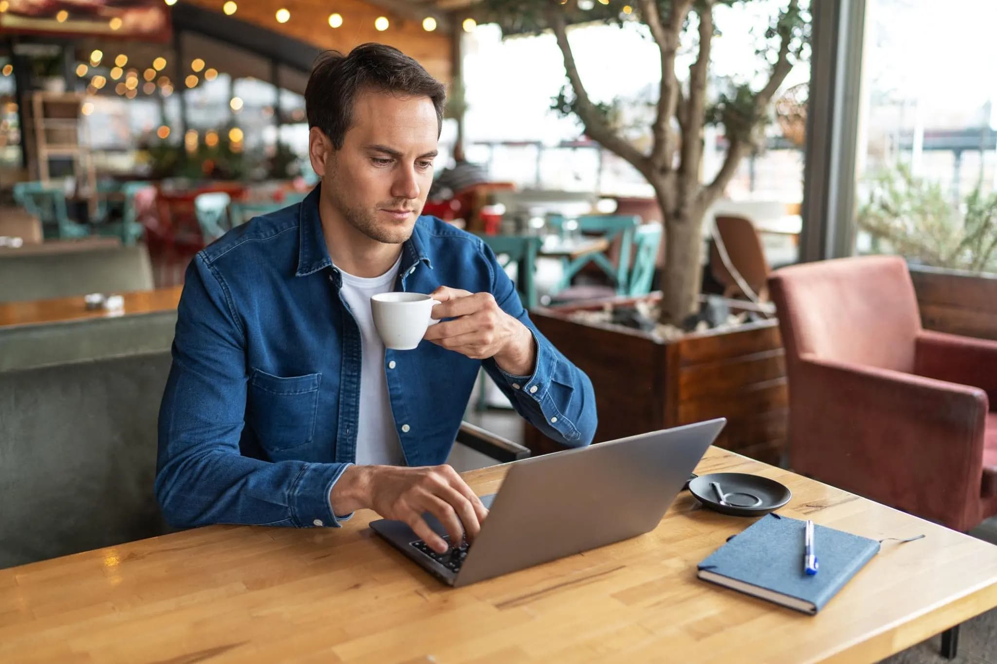 Focused entrepreneur in a cafe using his laptop to file a reinstatement application Florida online.